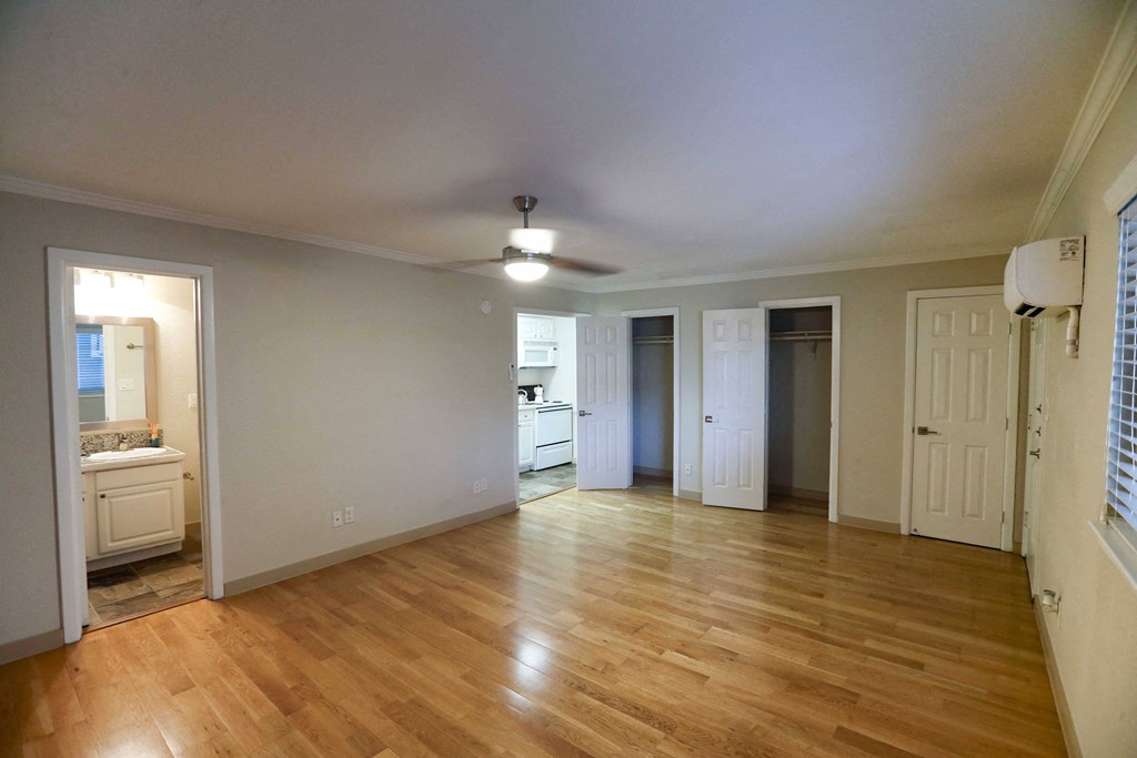 Studio apartment with kitchen and bathroom, featuring wood floors