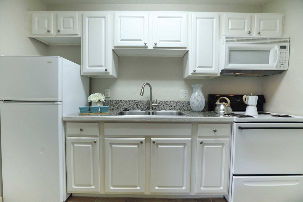 Kitchen in Studio apartment featuring wood floors, granite tile counters, and white cabinets