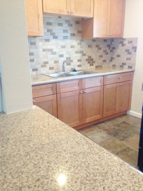View of kitchen with light counters, tile flooring, and brown cabinets