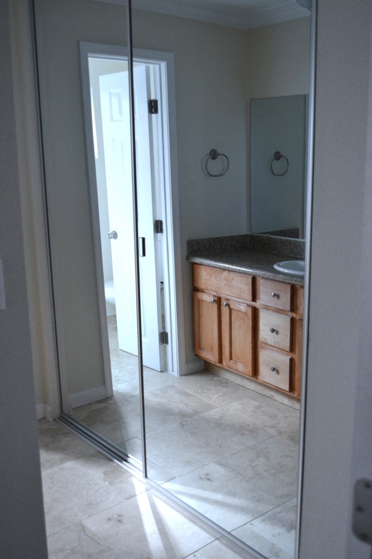 View of bathroom vanity through sliding glass mirror closet