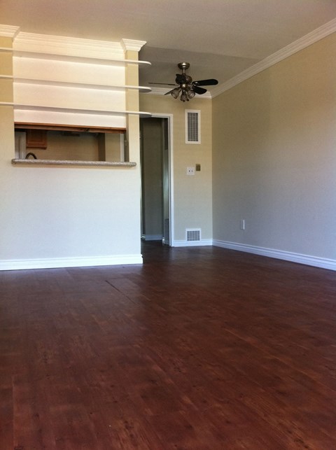 an empty living room with wood floors and a ceiling fan