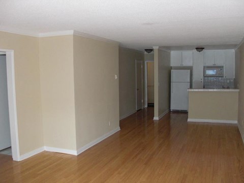an empty living room and kitchen with a wooden floor