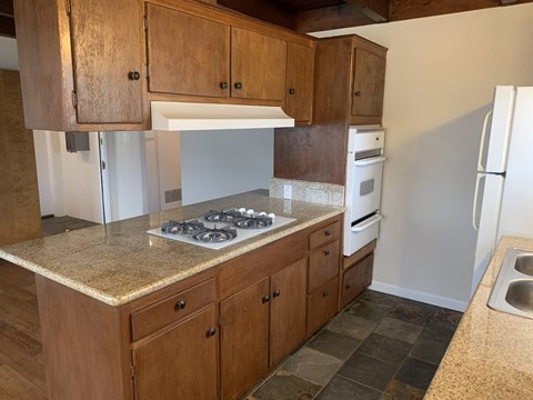 A kitchen with wooden cabinets and a granite countertop.