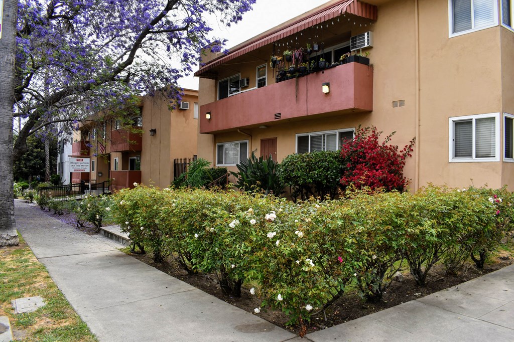 the exterior of an apartment building with a sidewalk and landscaping