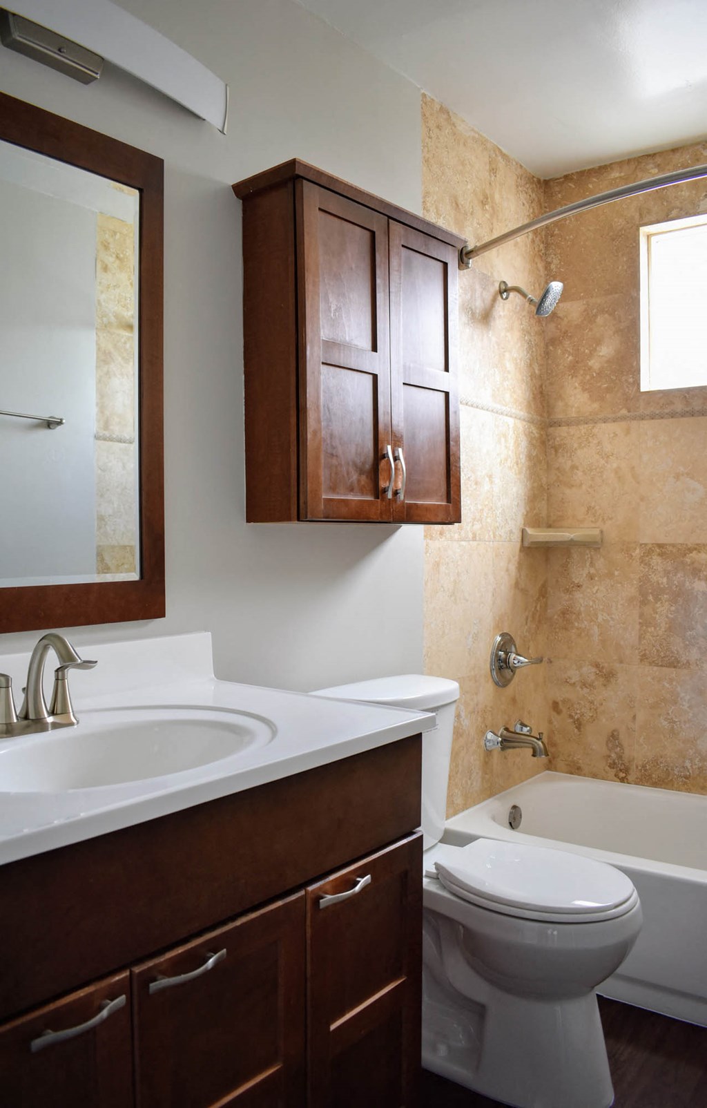 View of bathroom with inlaid sink, vanity, mirror, storage over toilet, toilet, tub shower combo with well lit window above