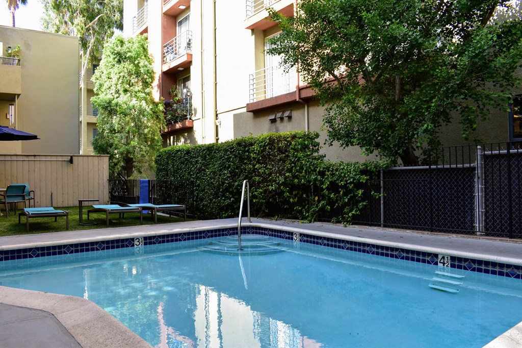 View of gated community pool with lounge chairs and seating