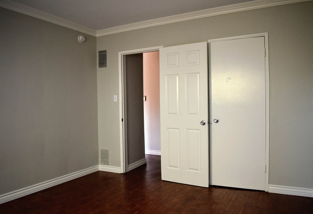 an empty living room with two doors and a door to a closet