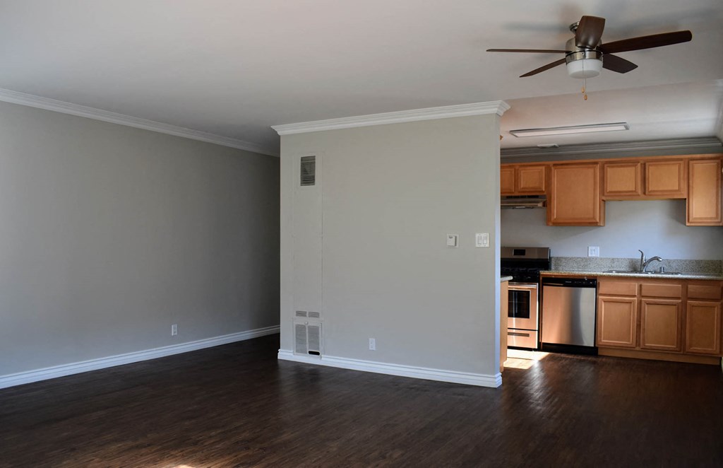 View of kitchen and dining area with wood look flooring, brown cabinets, stainless appliances and ceiling fan