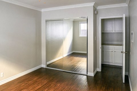a bedroom with a mirrored closet door and a hard wood floor