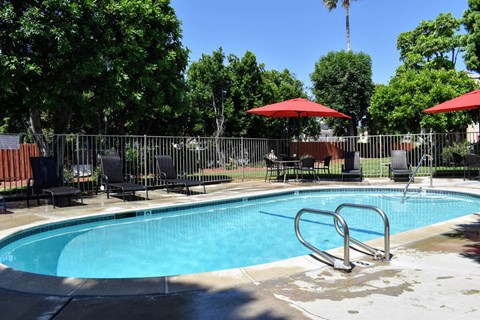 View of gated pool with lounge chairs and seating areas under umbrellas