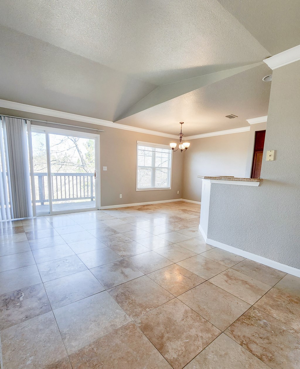 View of kitchen and dining area from living area, tile flooring, private patio/balcony access, well lit window