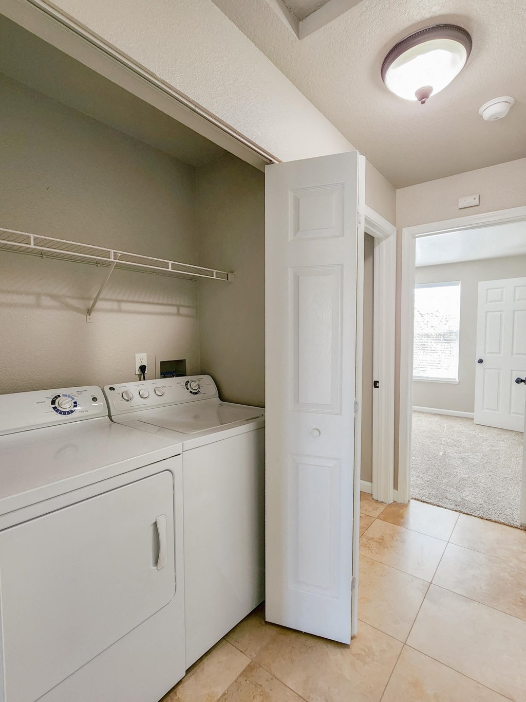 View of utility closet with washer and dryer and shelving above