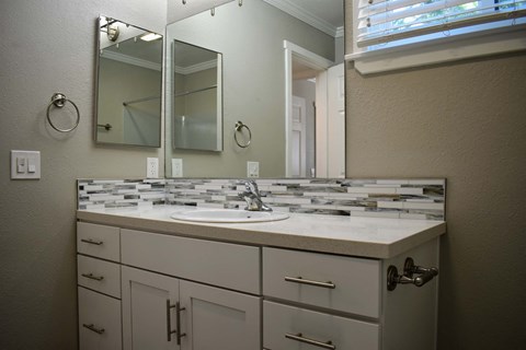 View of bathroom vanity with in laid sink, large mirror, medicine cabinet, and window