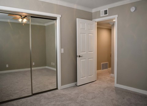 View of bedroom with carpet flooring, ceiling fan, and sliding glass mirror closet door