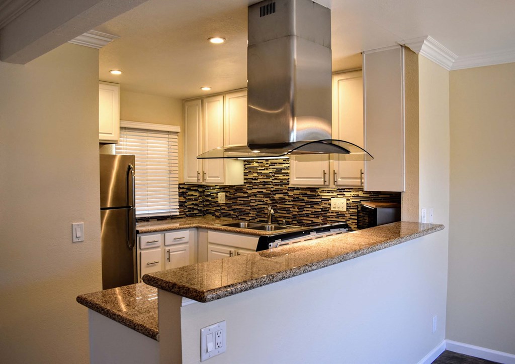 View of kitchen with stone counters, recessed lighting, tile backsplash and stainless appliances