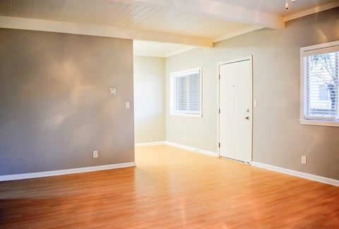 an empty living room with wood floors and a door