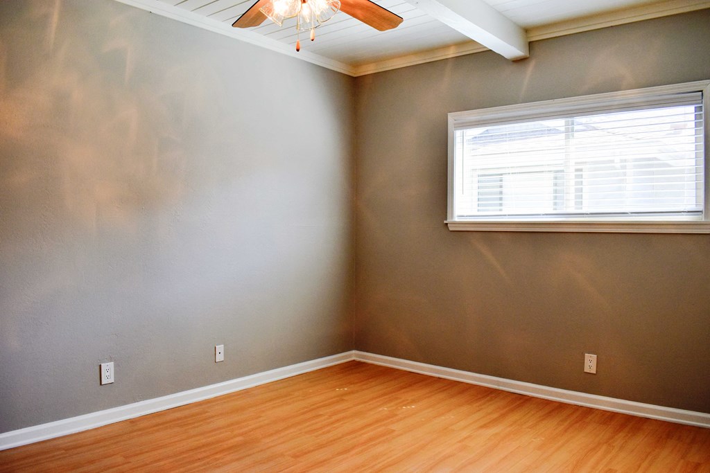 View of bedroom with wood look flooring, well lit window, and ceiling fan