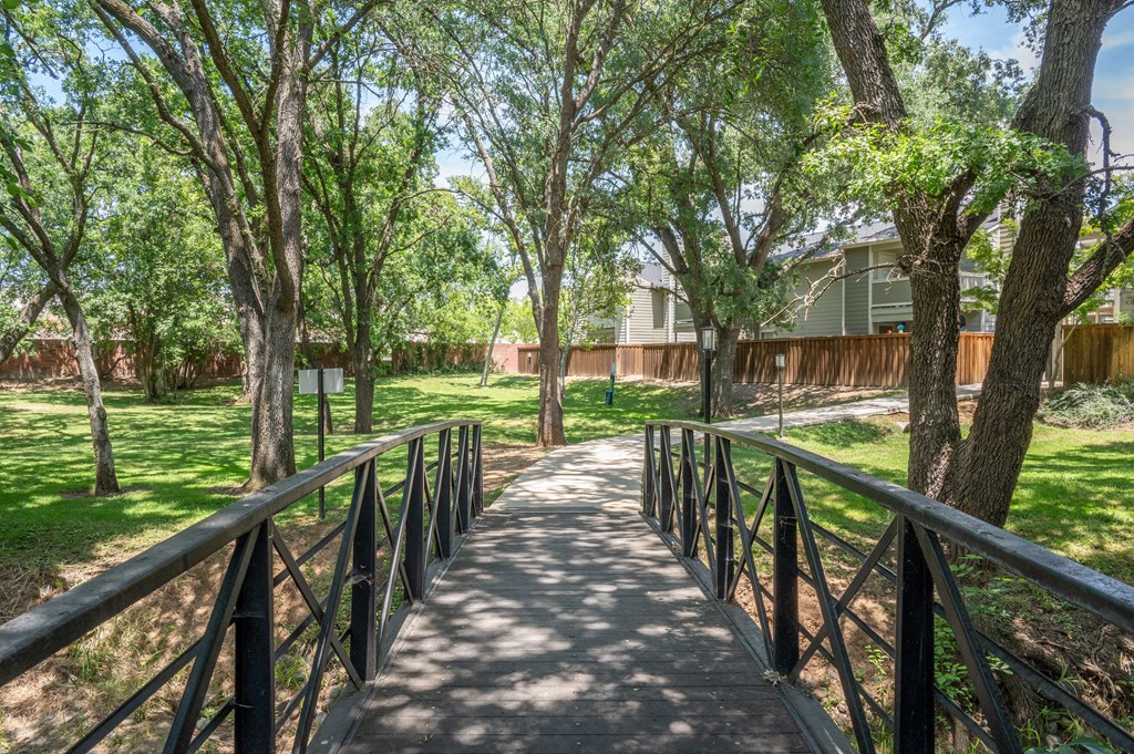 View of bridge crossing creek and courtyard with private patio/balcony