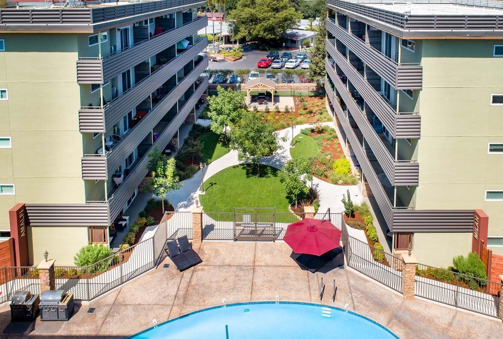 a view of a pool and a building with a red umbrella