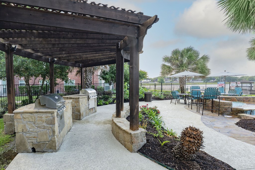 a patio with a fireplace and a pergola next to a pool
