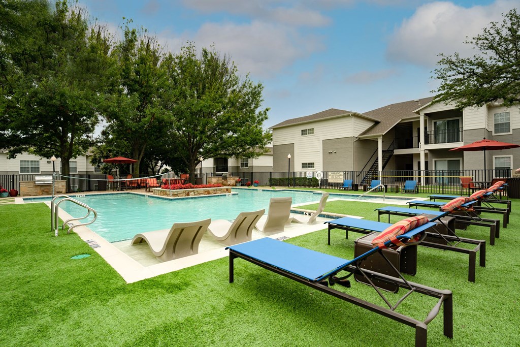 Luxurious pool view with lounge chairs and sitting area, lush grass and trees