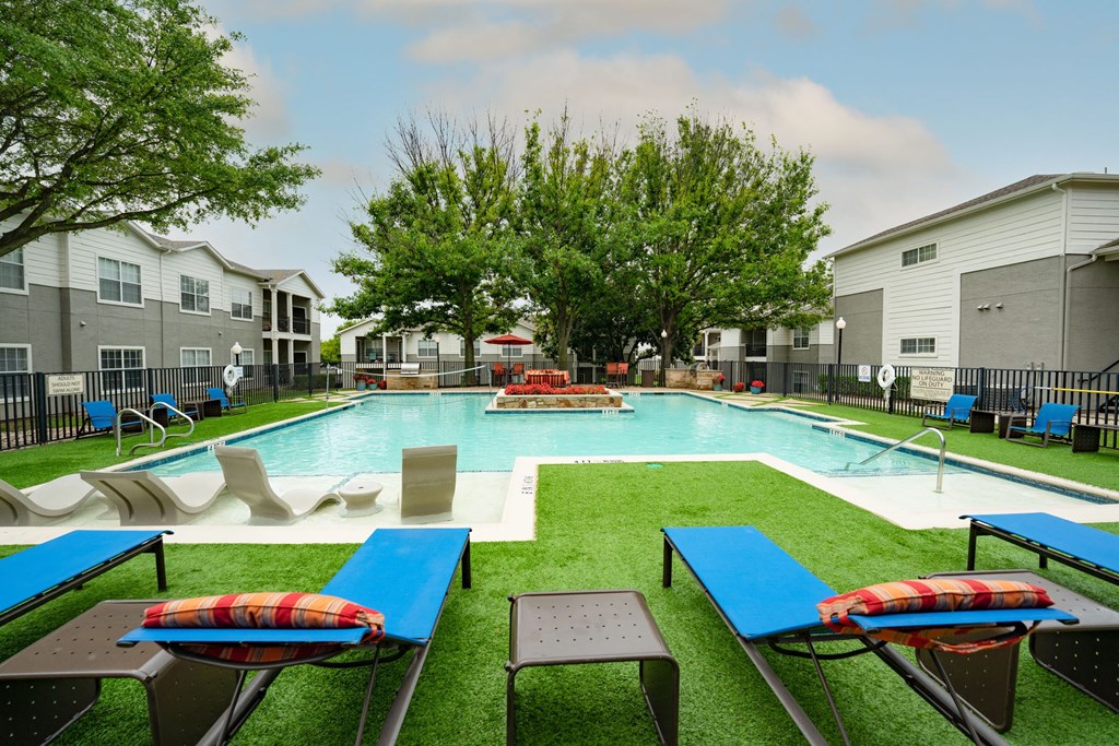 Luxurious pool view with lounge chairs and sitting area, lush grass and trees