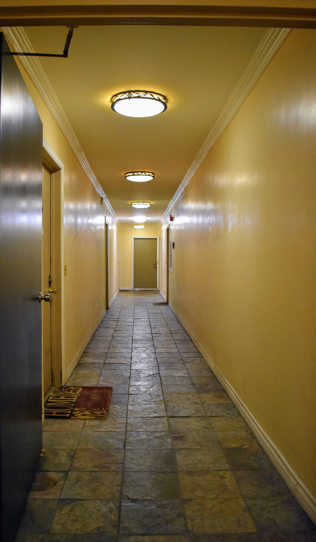 a hallway with yellow walls and a tile floor and a door
