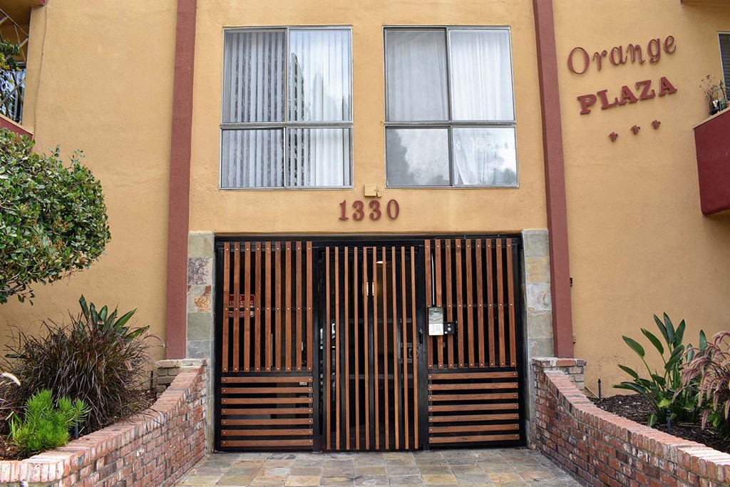 the entrance to an orange plaza building with a gate