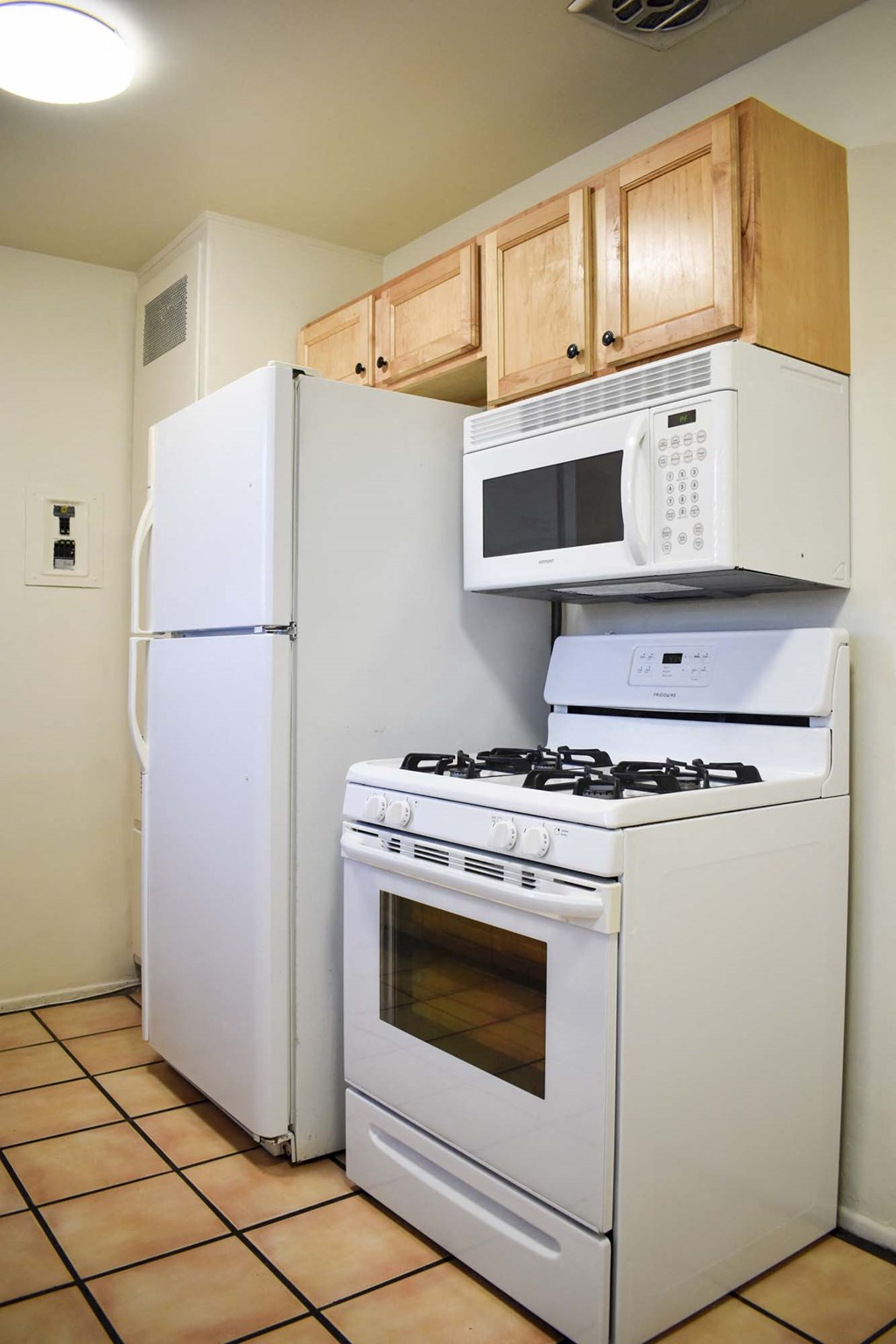 View of kitchen with white appliances, brown cabinets, and tile flooring