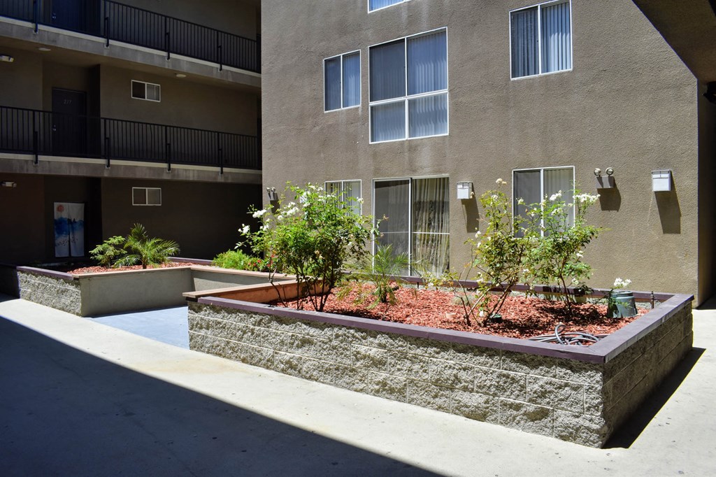 the courtyard of an apartment building with a stone retaining wall