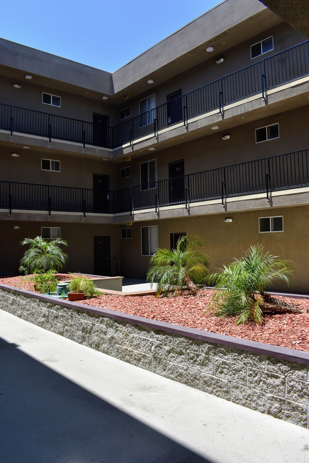 an apartment building with gravel and plants in front of it