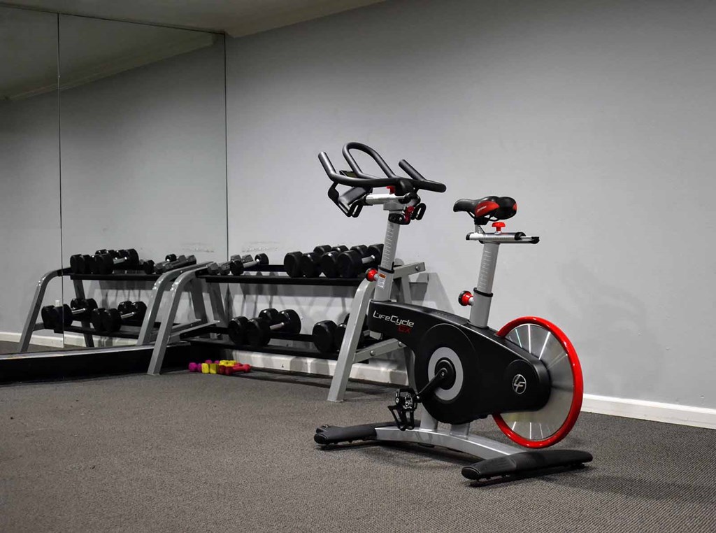 View of community gym spin bike and free weights in the background