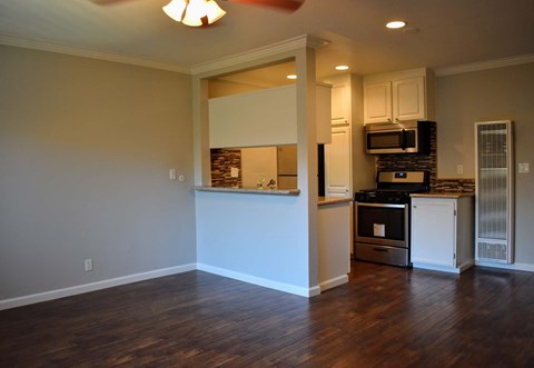 an empty living room and kitchen with a wood floor