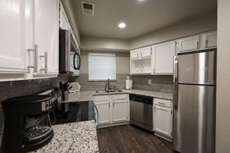 View of kitchen with granite counters, stainless appliances, window about sink , and wood like flooring