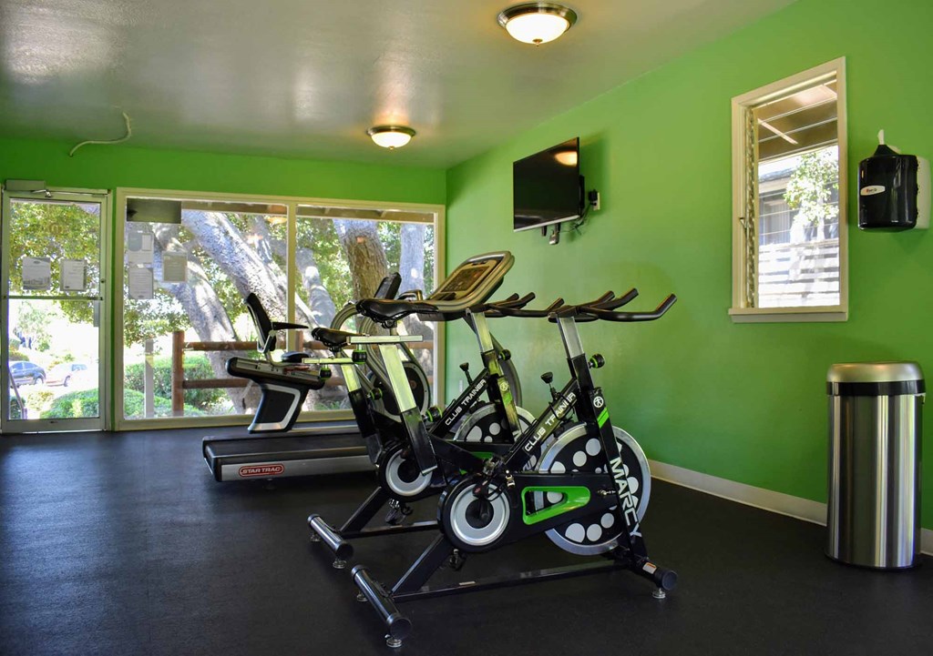 community fitness center with stationary bikes, treadmill, and view outside