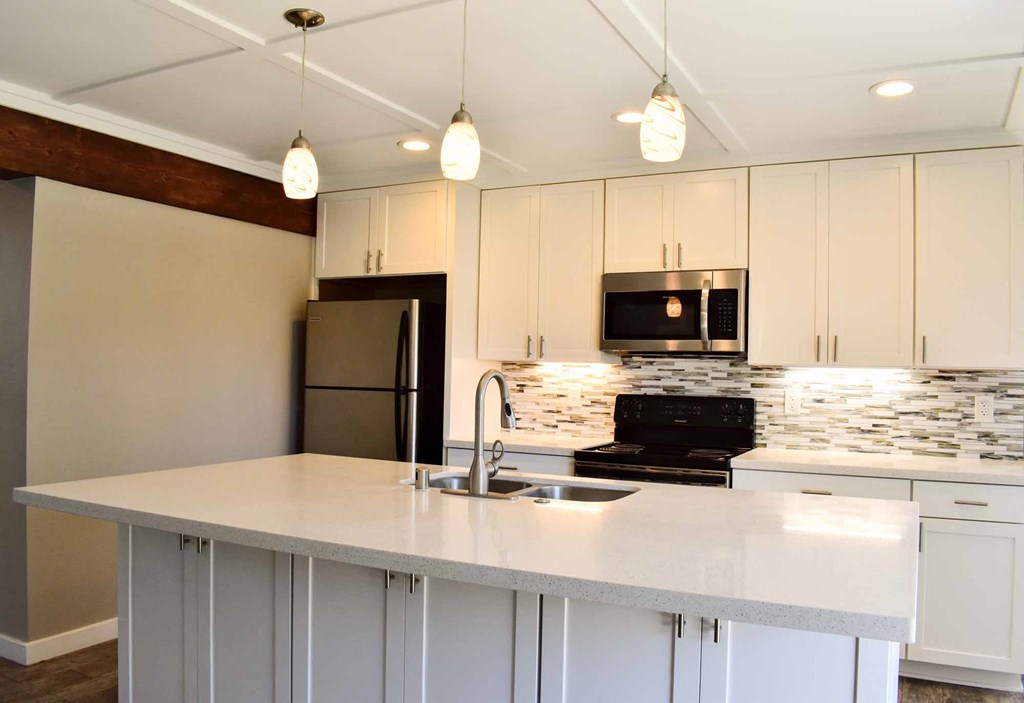 kitchen with island, all white countertops, white cabinets, stainless appliances, and tile backsplash
