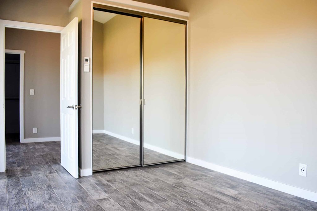 bedroom view of sliding mirror door closet and into hallway, has wood look flooring