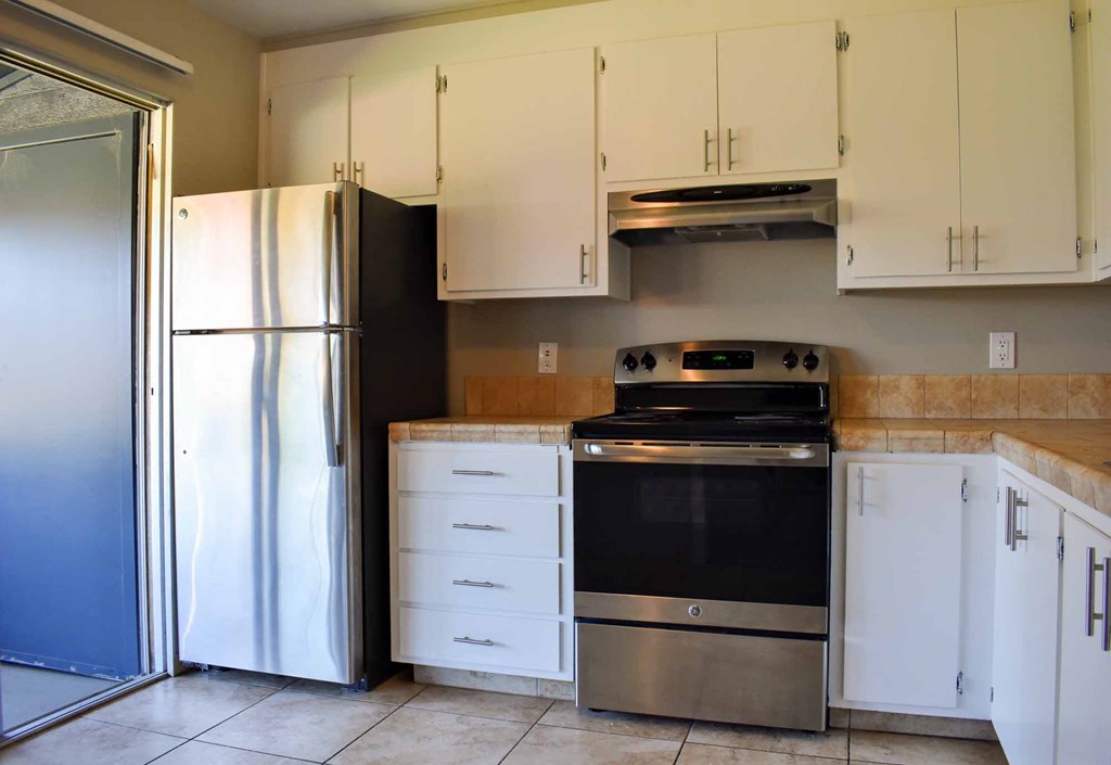 kitchen with tile flooring, light countertops, stainless appliances, and white cabinets