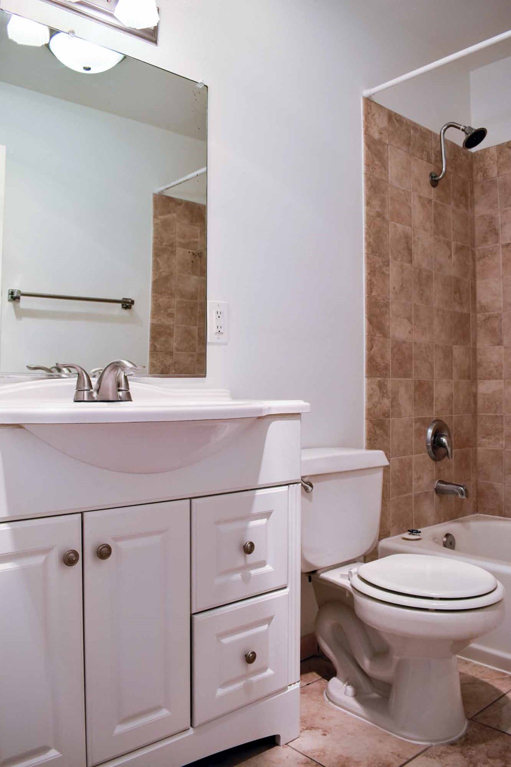 bathroom with in laid sink, white cabinets, toilet, and tiled tub shower combo