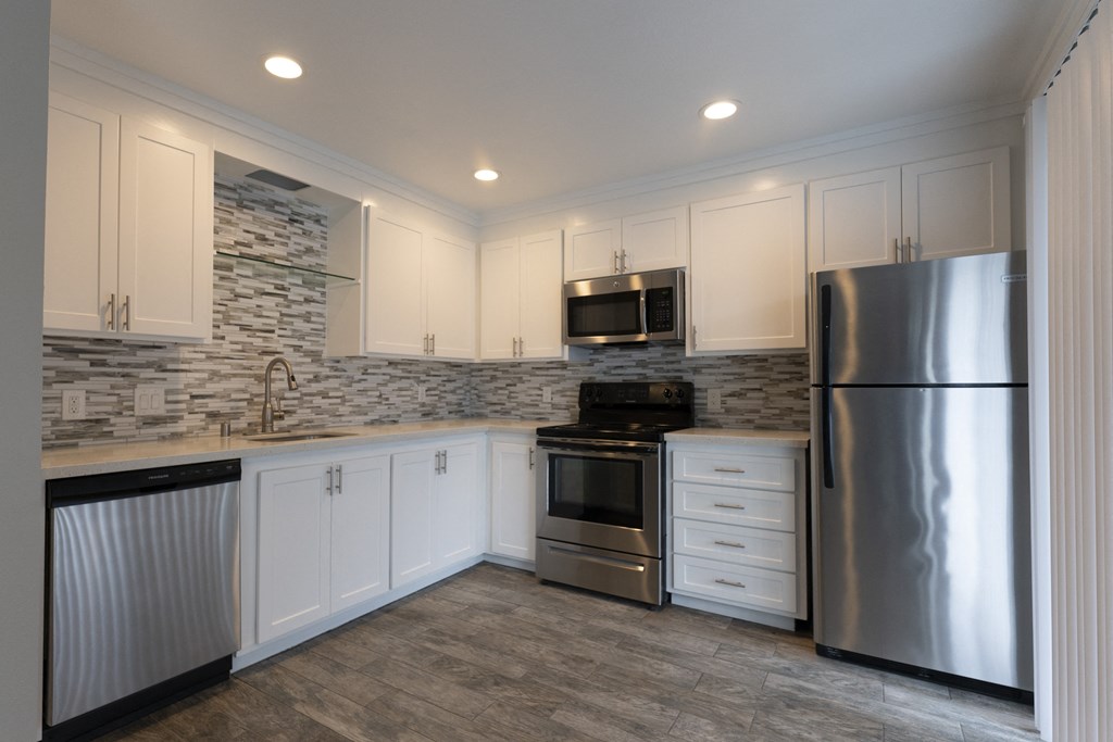 a kitchen with white cabinets and stainless steel appliances