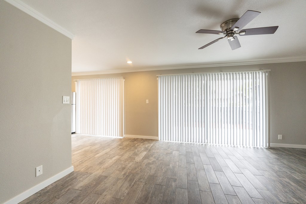 living room with wood look flooring and access to private patio/balcony with ceiling fan and vertical blinds