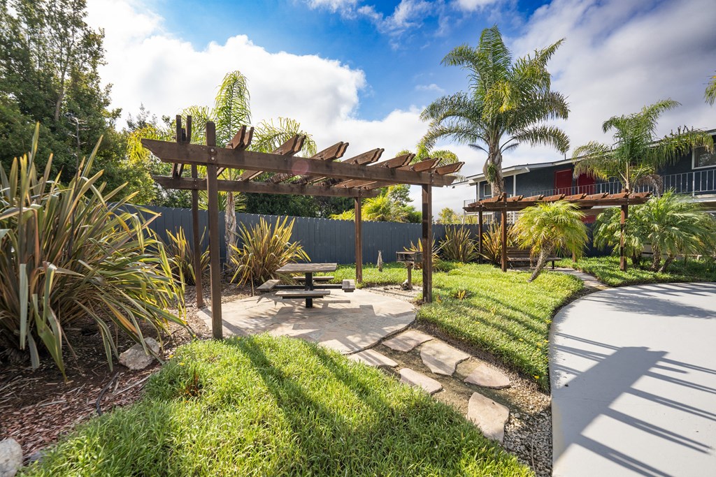 a garden with a picnic table and a pergola