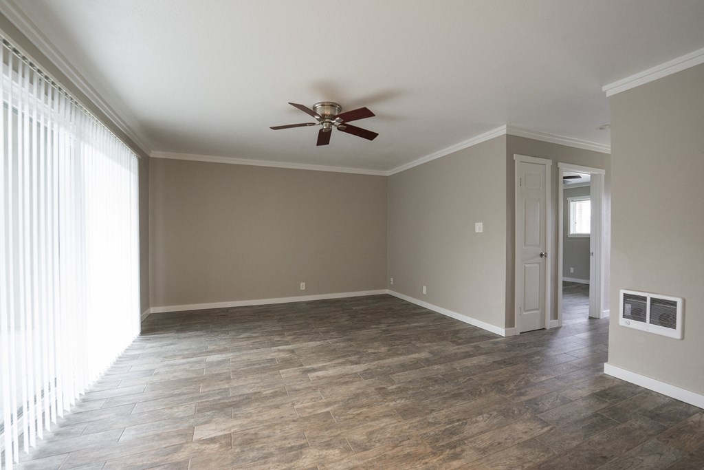 an empty living room with a ceiling fan