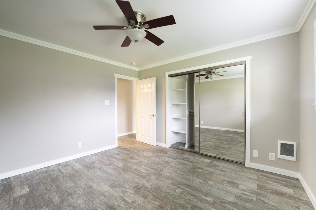 a bedroom with a ceiling fan and a closet with a mirrored door