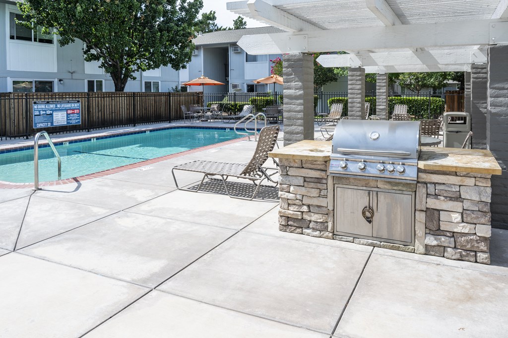 a patio with a grill next to a swimming pool