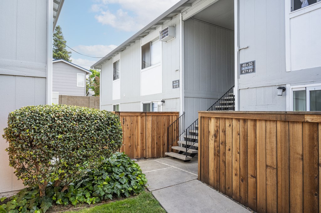 the back yard of a white apartment building with a wooden fence
