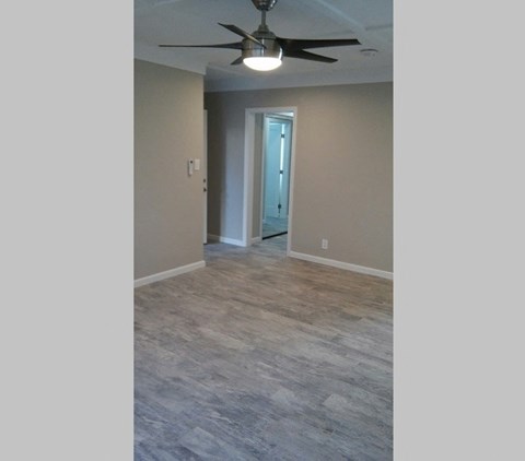 an empty living room with a ceiling fan