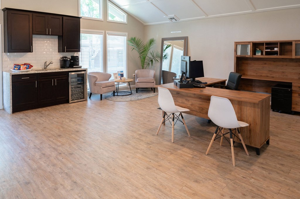 an office with a desk and chairs and a kitchen with a table and chairs