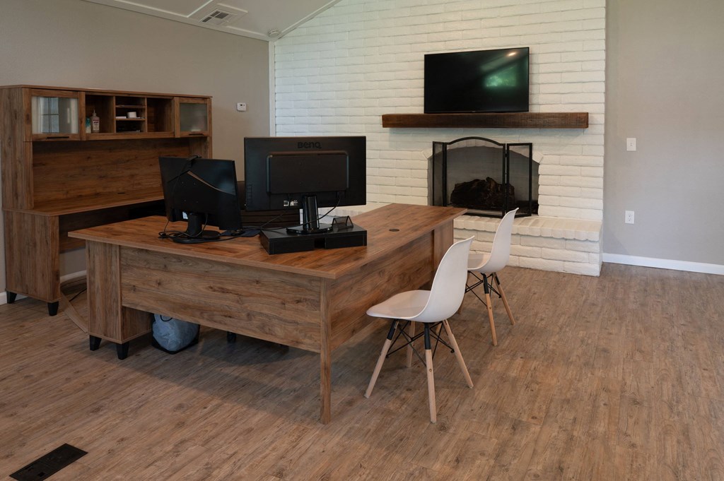a home office with a wooden desk and two televisions