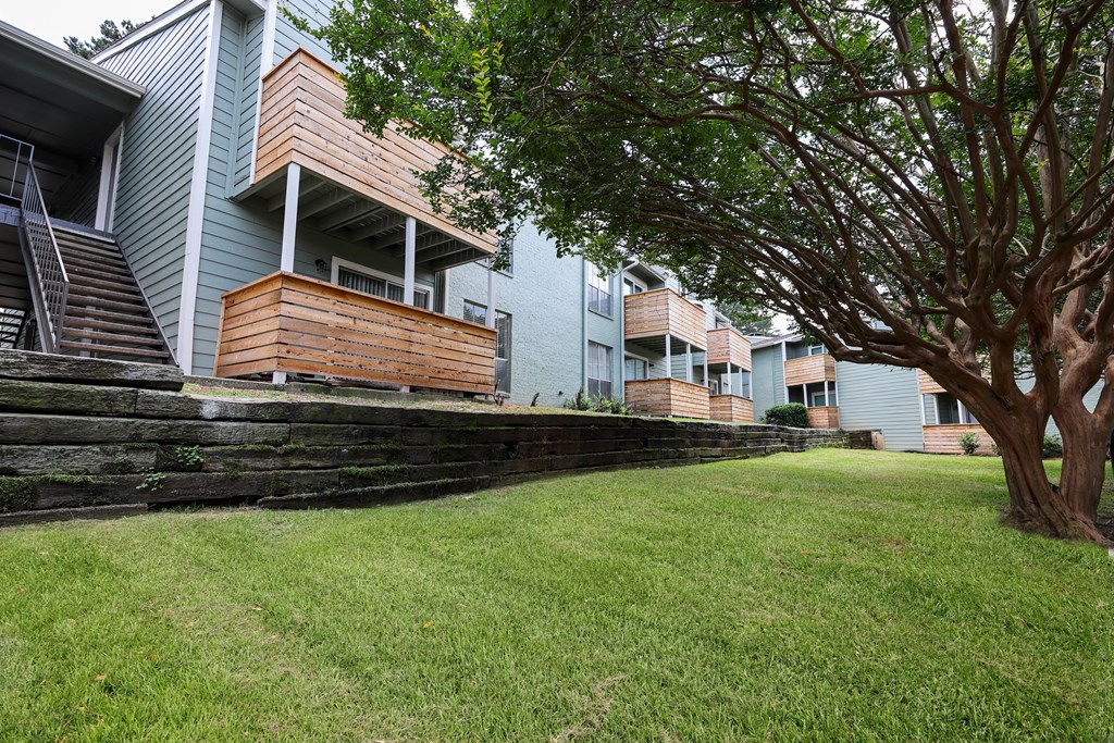 a grassy area with a tree in front of an apartment building